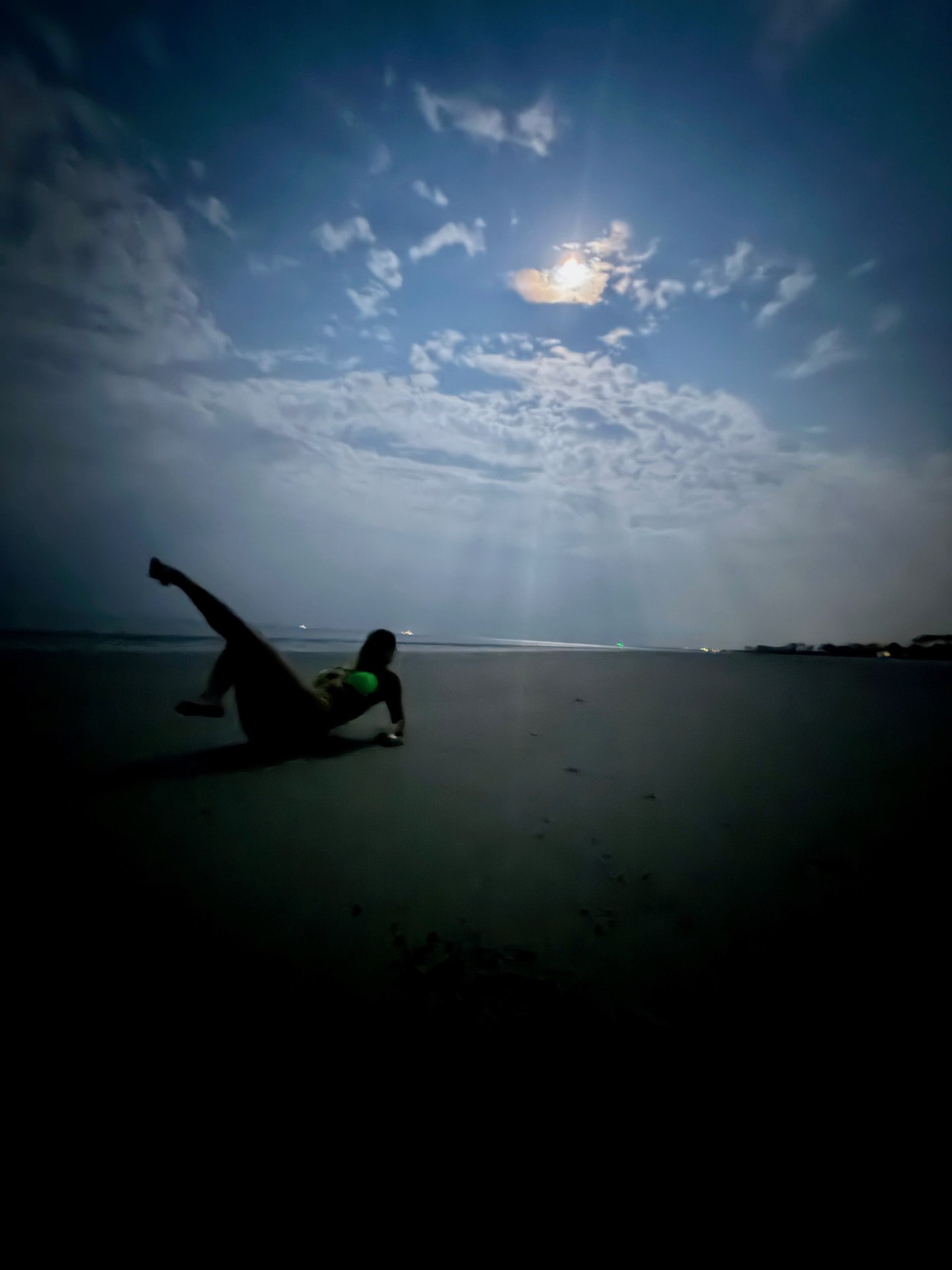 Figure on wet sand under moonlight at the shoreline.